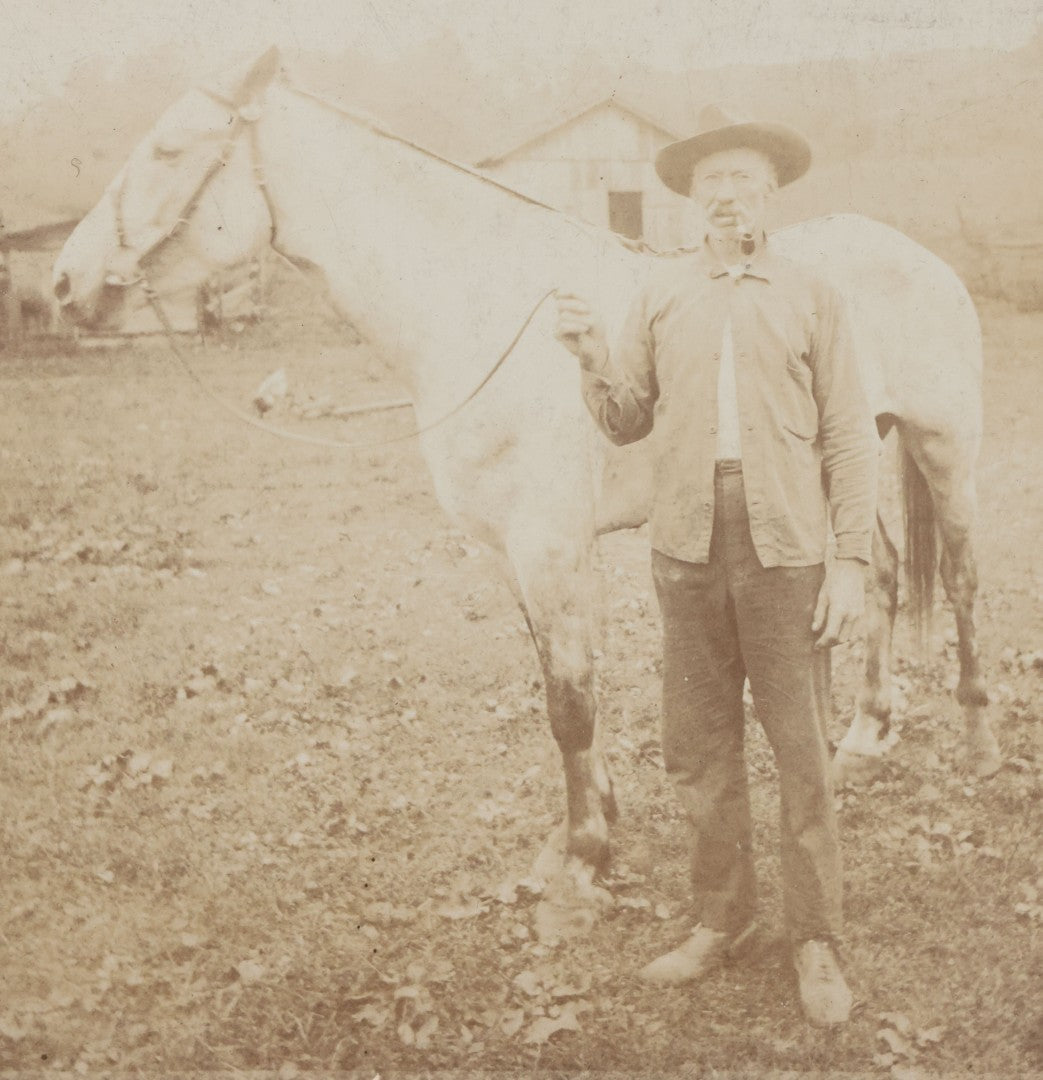 Lot 128 - Antique Boarded Photograph Of An Elderly Cowboy Smoking A Pipe Beside His White Horse