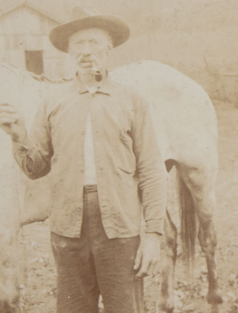 Lot 128 - Antique Boarded Photograph Of An Elderly Cowboy Smoking A Pipe Beside His White Horse