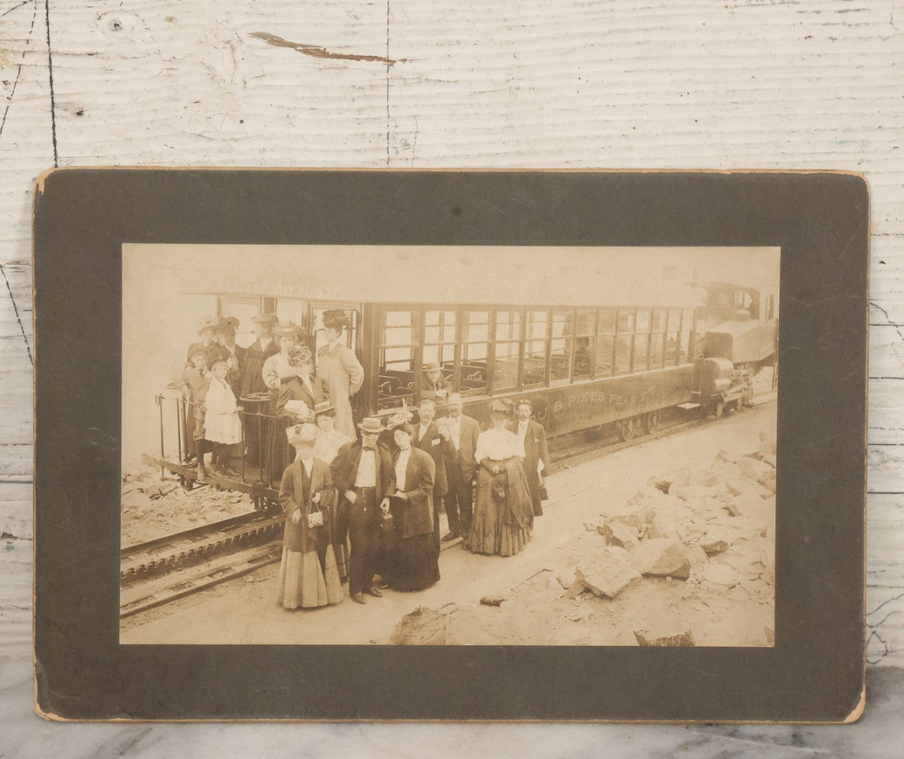 Lot 129 - Antique Boarded Souvenir Photograph Of Travelers Beside Rail Car On The Manitou & Pike's Peak Cog Railway, Rocky Mountains, Colorado, Photo By J.G. Hiestand, Official Photographer, Dated 1907
