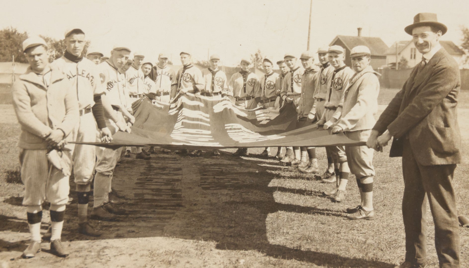 Lot 139 - Antique Boarded Photograph Of The Players Of A Baseball Team In Uniform Posing With A Large Flag, Uniforms Say "Royal League" With Patches Visible