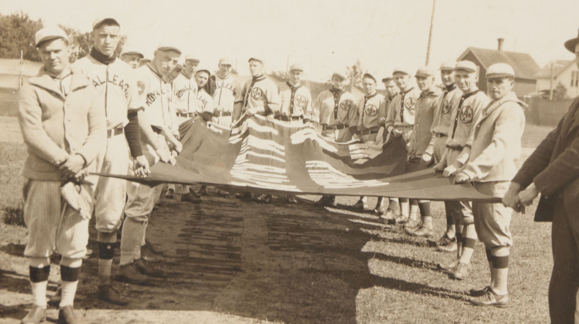 Lot 139 - Antique Boarded Photograph Of The Players Of A Baseball Team In Uniform Posing With A Large Flag, Uniforms Say "Royal League" With Patches Visible