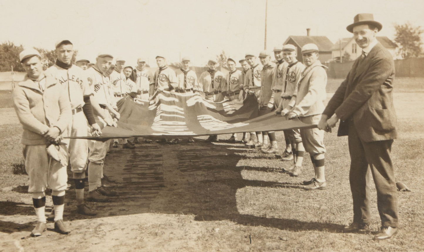 Lot 139 - Antique Boarded Photograph Of The Players Of A Baseball Team In Uniform Posing With A Large Flag, Uniforms Say "Royal League" With Patches Visible