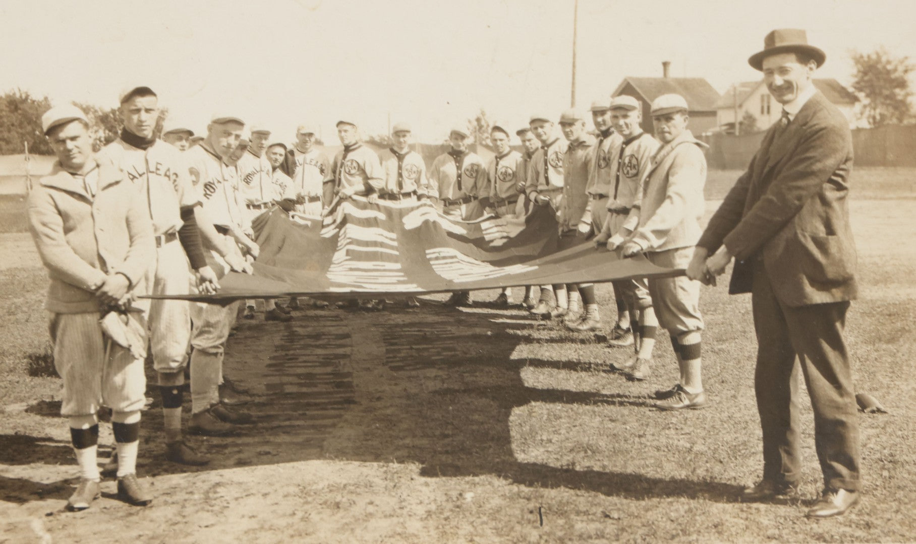 Lot 139 - Antique Boarded Photograph Of The Players Of A Baseball Team In Uniform Posing With A Large Flag, Uniforms Say "Royal League" With Patches Visible