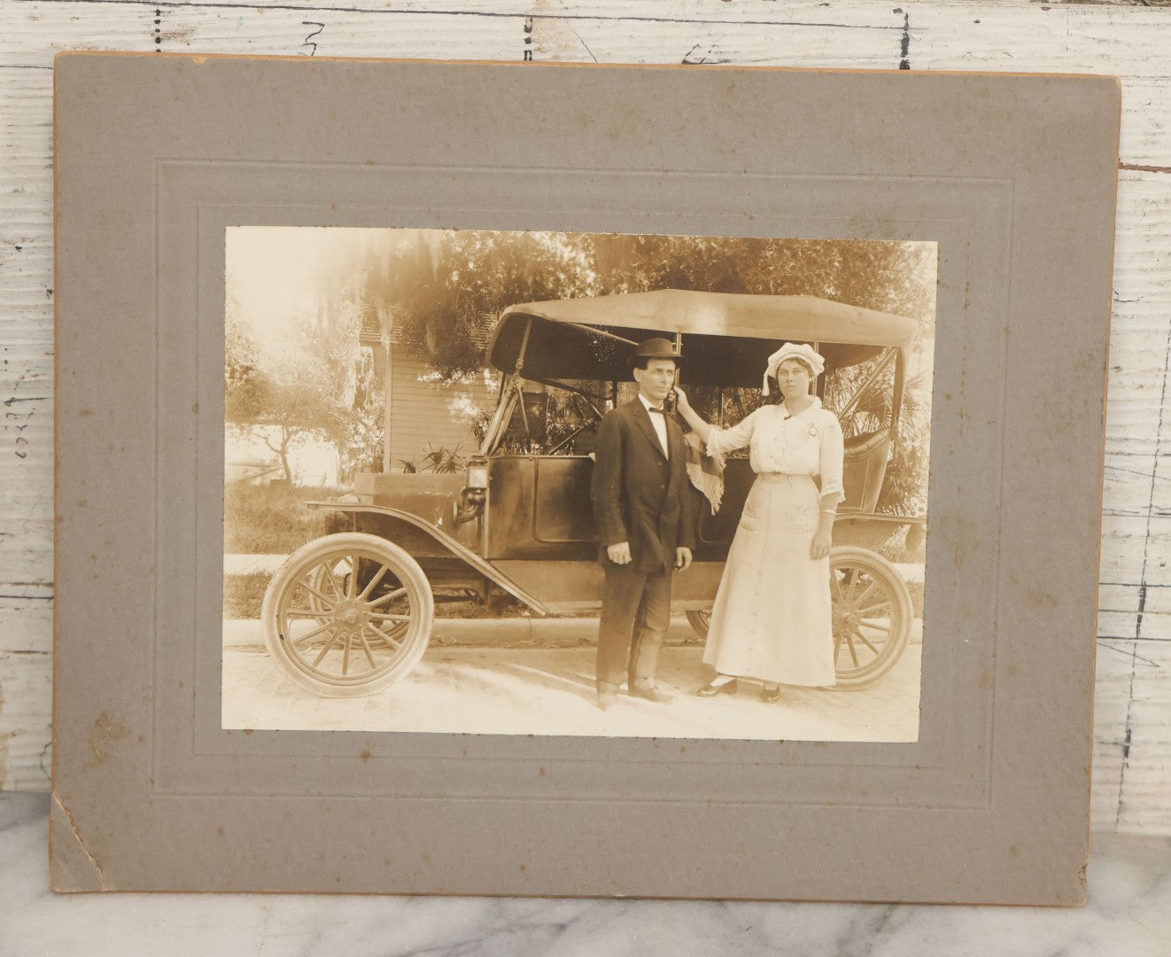 Lot 141 - Pair Of Antique Boarded Photographs Including Man And Woman Couple Posing Beside Early Automobile, Woman Does Not Look Thrilled And Man Seems To Know It, And Man Driving Away Without Her