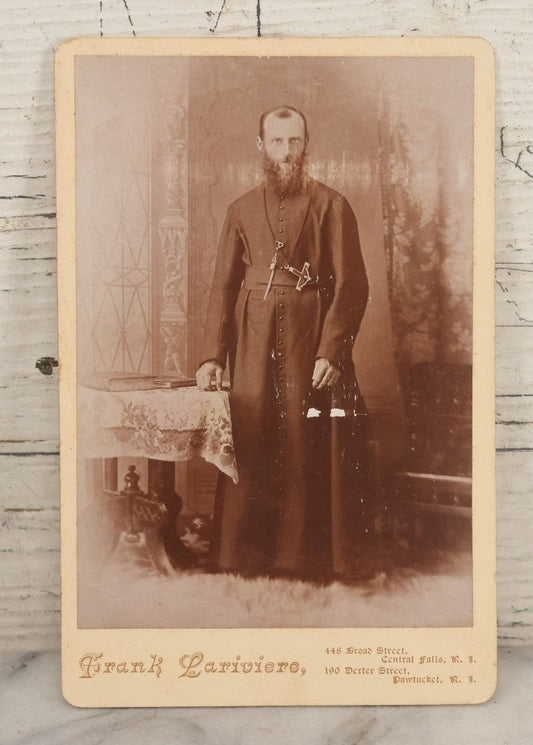 Lot 019 - Antique Cabinet Card Photograph Of A Bearded Priest In Black Robe With Large Pectoral Crucifix Tucked In Belt, Frank Lariviere, Photographer, Central Falls & Pawtucket, Rhode Island