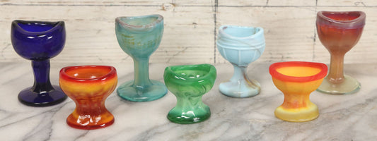 Lot 023 - Grouping Of Seven Vintage Colorful Swirled Slag Glass Eye Wash Cups, Including Cadmium, Other Black Light Reactive Colors, Blue, Green, Red, Etc., As Seen, Up To 2-5/8" Height