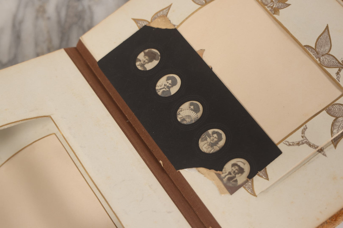 Lot 012 - Antique Victorian Photo Album With Wood Cover And Silverplate Emblem, Containing Twenty Antique Photographs Of Various Types, Including Man In Office, Children With Pram, Man With White Beard, Note Binding Wear Cover Loosening
