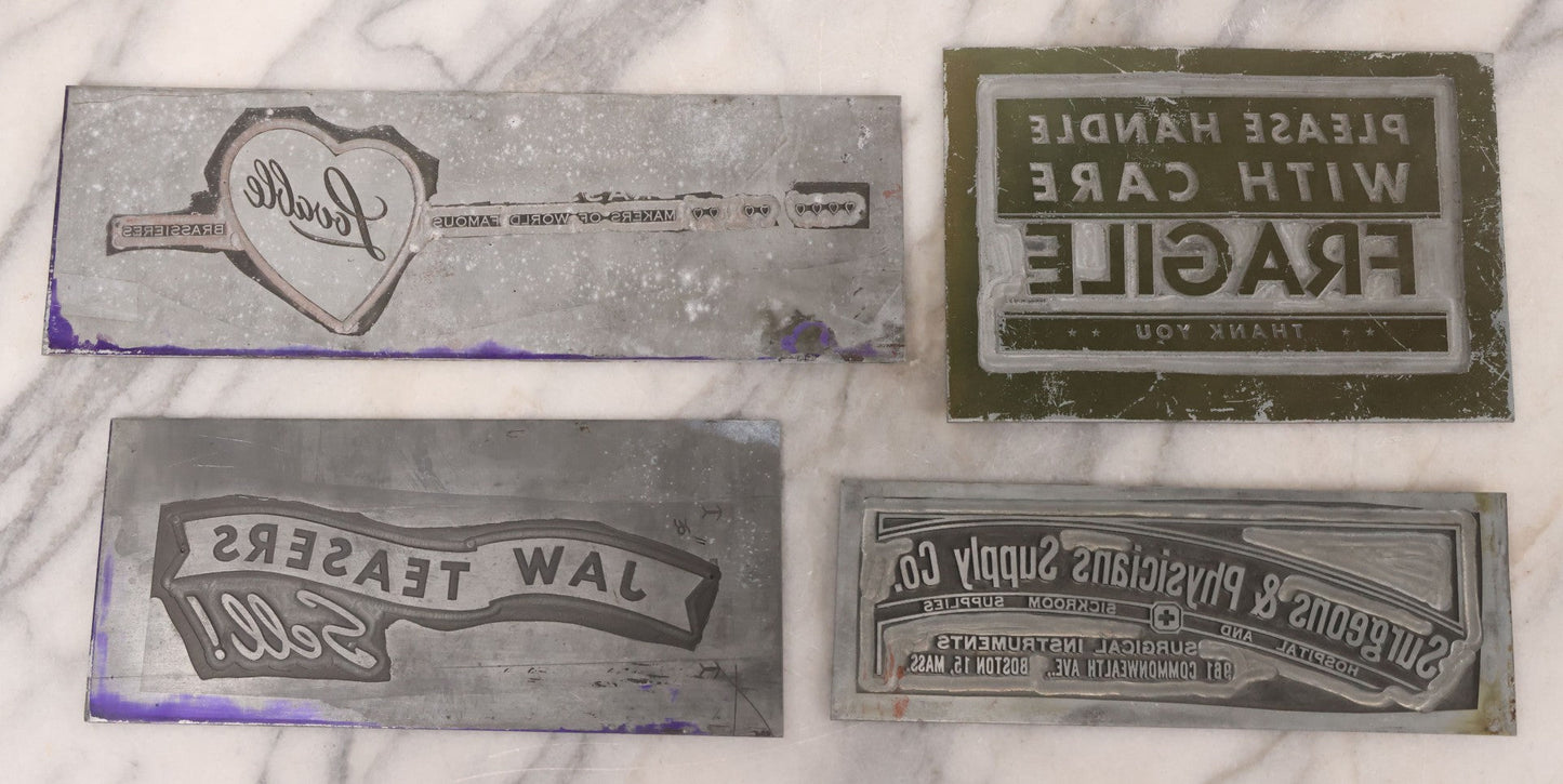 Lot 077 - Grouping Of Four Vintage Metal Printing Plates Including Loveable Brassieres, Surgeons & Physicians Supply Co., Jaw Teasers, And Fragile Stamp