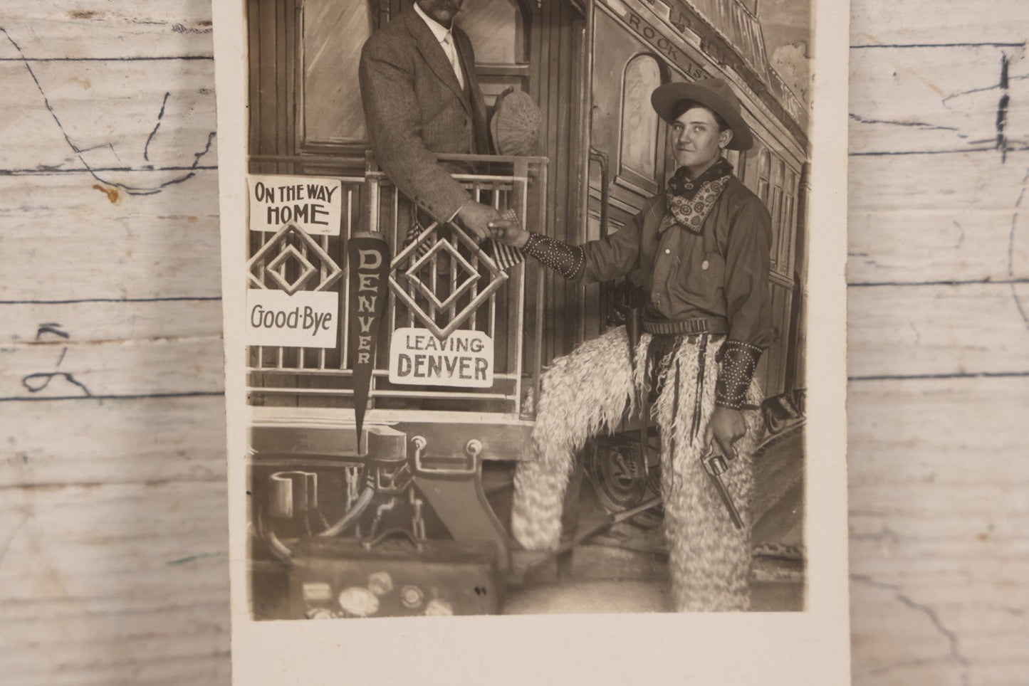 Lot 083 - Antique Real Photo Postcard R.P.P.C. Showing Young Man Dressed As Cowboy Shaking Hands With Older Man On Faux Train Photography Set In Denver, Colorado