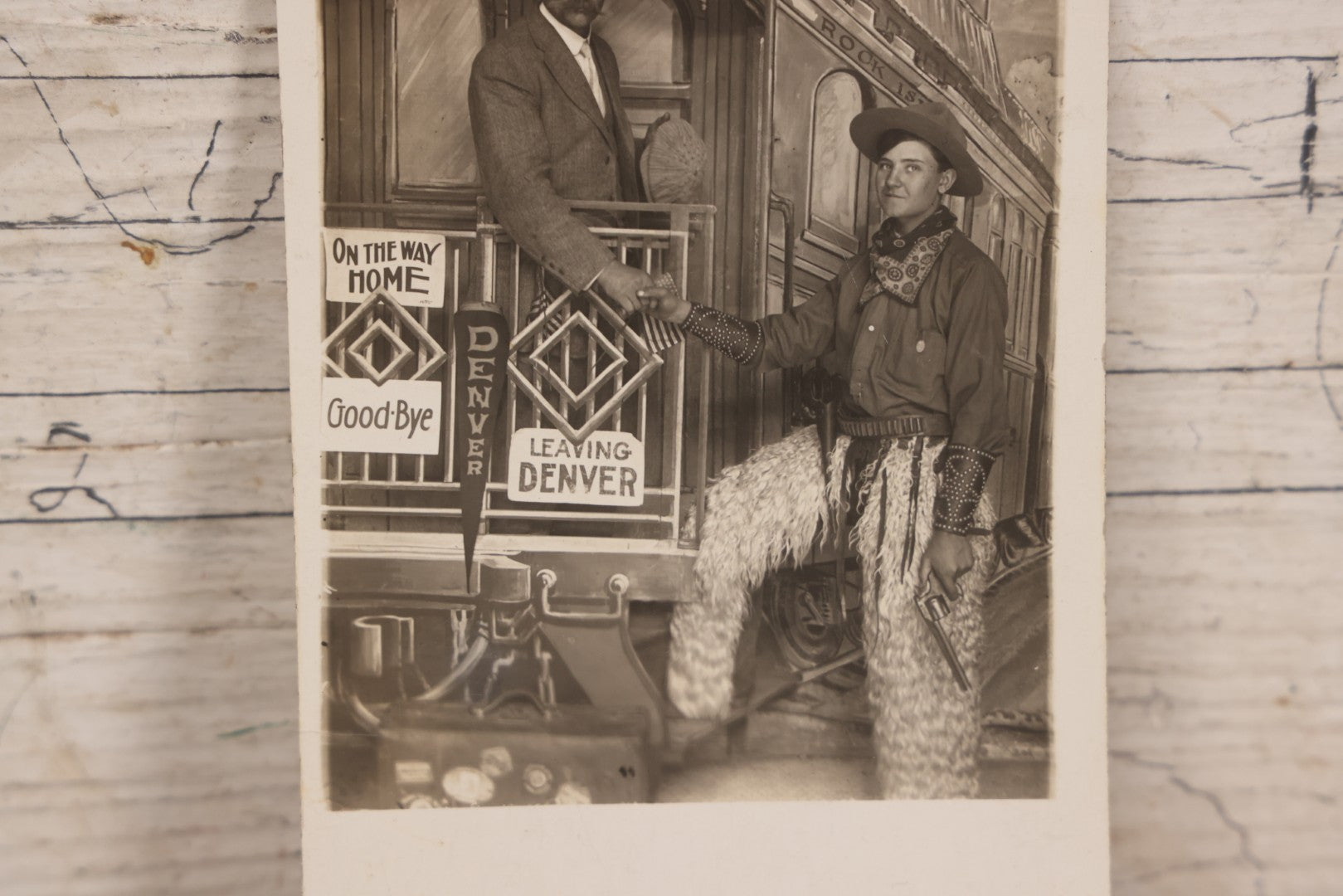 Lot 083 - Antique Real Photo Postcard R.P.P.C. Showing Young Man Dressed As Cowboy Shaking Hands With Older Man On Faux Train Photography Set In Denver, Colorado