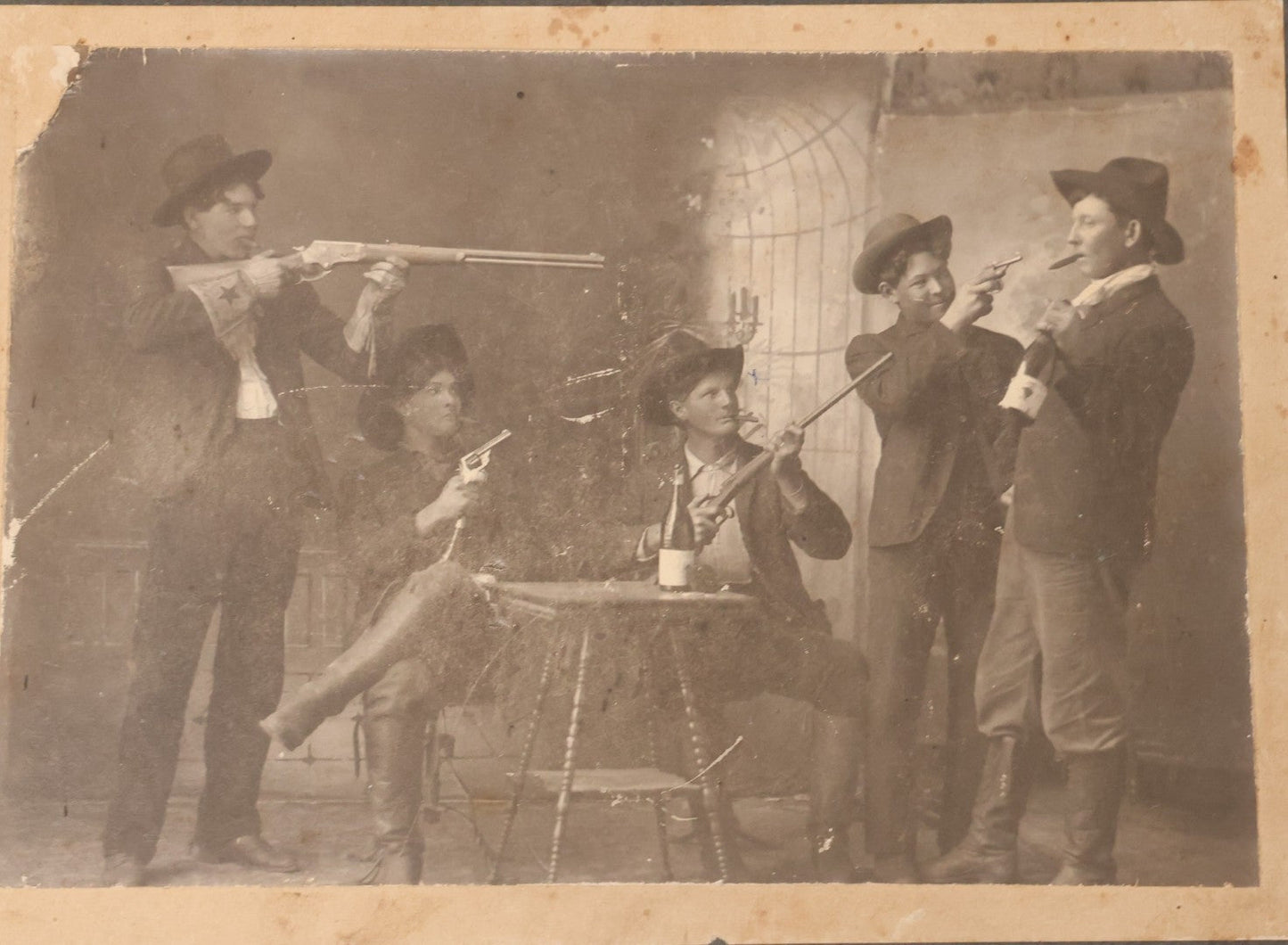 Lot 086 - Antique Boarded Studio Photograph Of Four Boys Drinking, Smoking, And Pointing Guns At Their Buddy