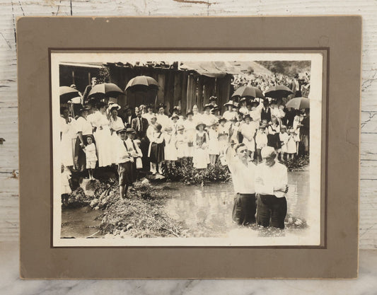 Lot 006 - Antique Boarded Photograph Of A Crowd Looking On As An Elderly Man Is Baptised In A Small Pond