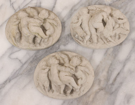 Lot 078 - Grouping Of Three Vintage Concrete Wall Plaques Depicting Cherubs In Different Scenes, Including With Lamb