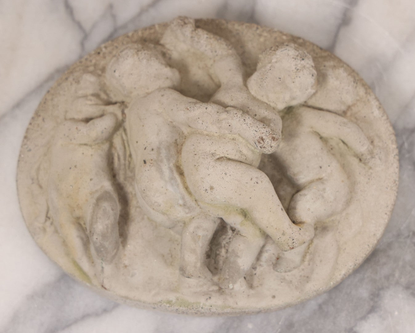 Lot 078 - Grouping Of Three Vintage Concrete Wall Plaques Depicting Cherubs In Different Scenes, Including With Lamb