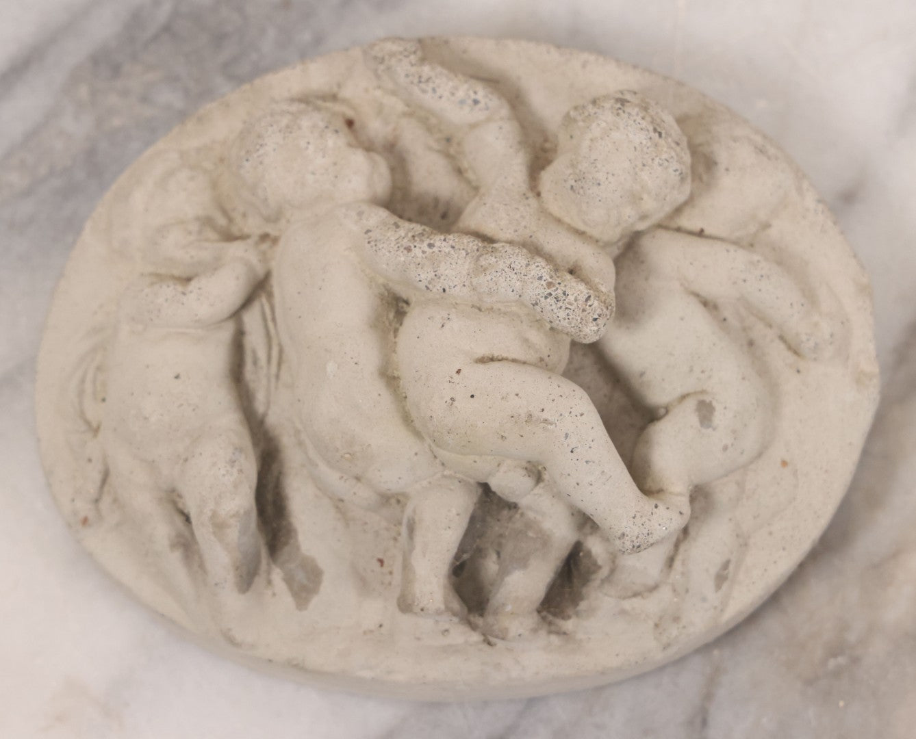 Lot 078 - Grouping Of Three Vintage Concrete Wall Plaques Depicting Cherubs In Different Scenes, Including With Lamb