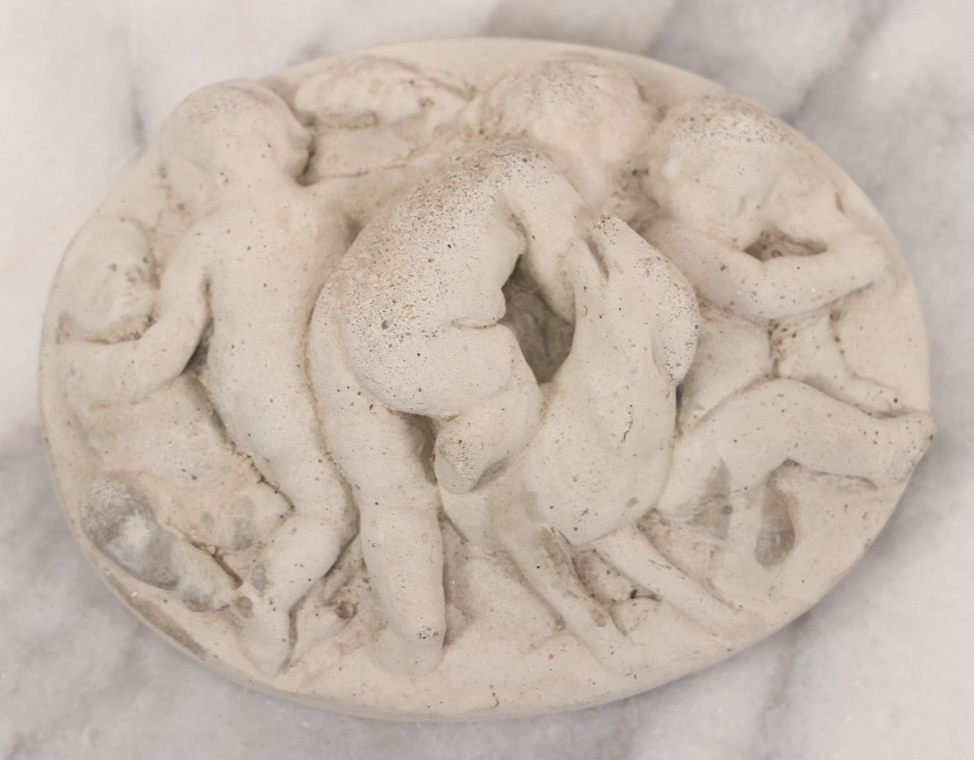 Lot 078 - Grouping Of Three Vintage Concrete Wall Plaques Depicting Cherubs In Different Scenes, Including With Lamb
