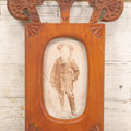 Lot 083 - Antique Folk Art Hand Carved Wooden Photo Frame With Crossed Axes, Spear Motifs, With Cabinet Card Photo Of Little Boy, 7" x 10-1/4"