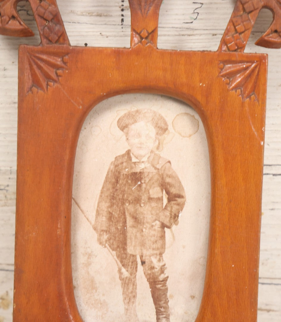 Lot 083 - Antique Folk Art Hand Carved Wooden Photo Frame With Crossed Axes, Spear Motifs, With Cabinet Card Photo Of Little Boy