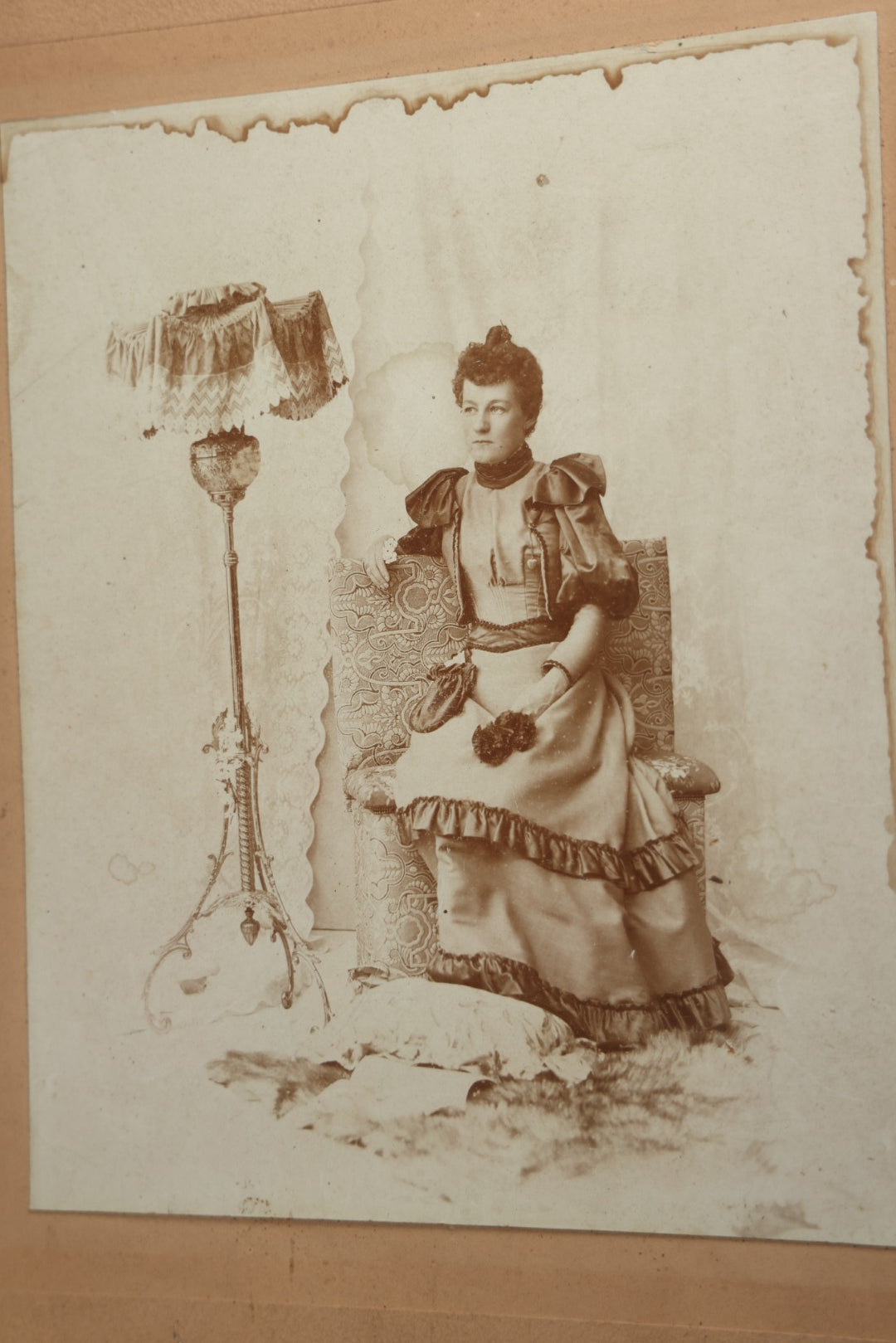 Lot 130 - Antique Boarded Photograph Of A Well Dressed Woman Posing On An Elaborate Set With Piano Lamp