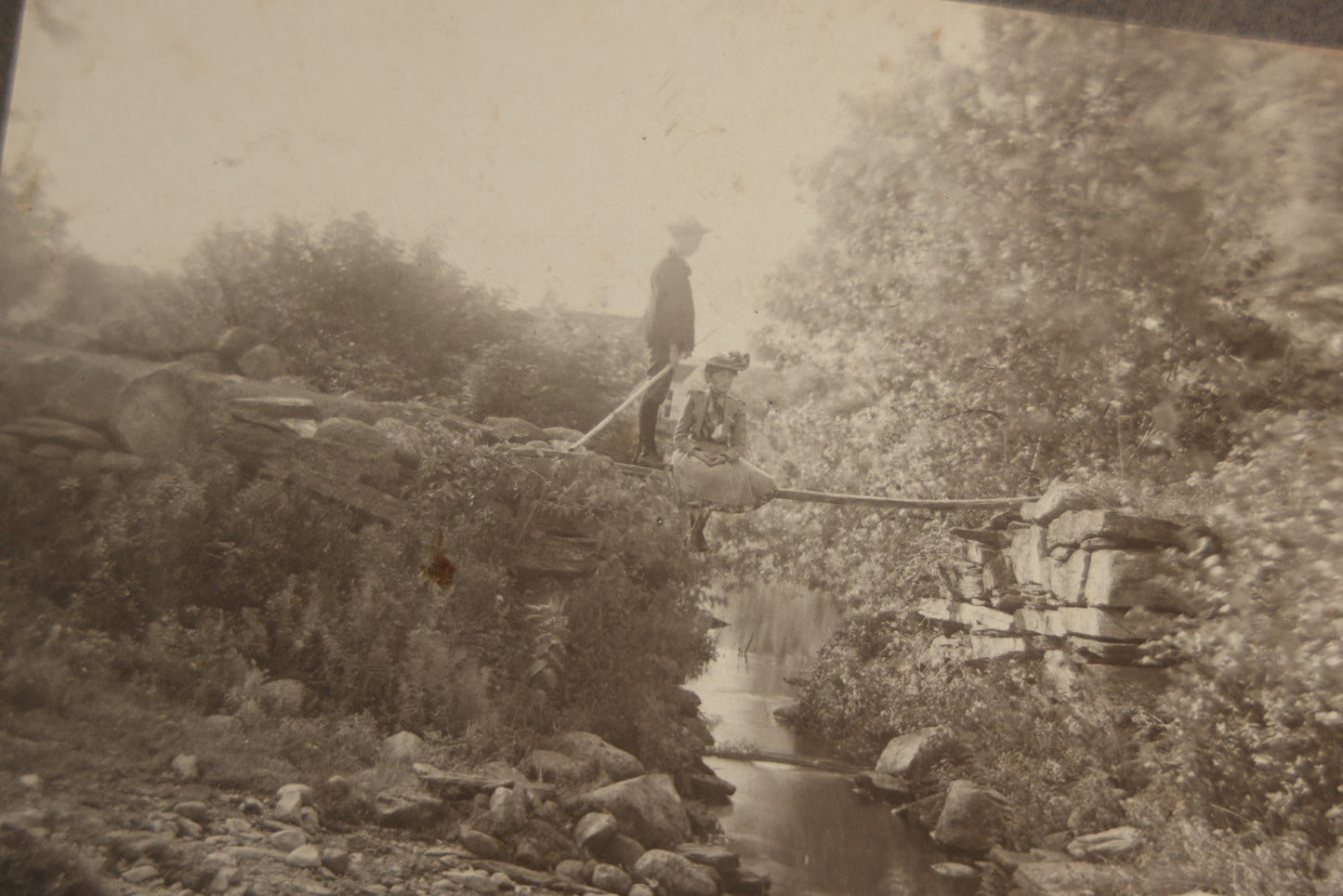 Lot 131 - Pair Of Antique Boarded Photographs Of Outdoor Scenes, Including Boy And Girl On Primitive Stick Bridge Crossing Creek, Canoe