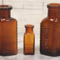 Lot 044 - Grouping Of Three Vintage Amber Glass Poison Bottles Including Tincture Of Iodine Bottle With Skull And Crossbones, Others With Embossed "Poison" Lettering, 2" and 3-5/8" Heights