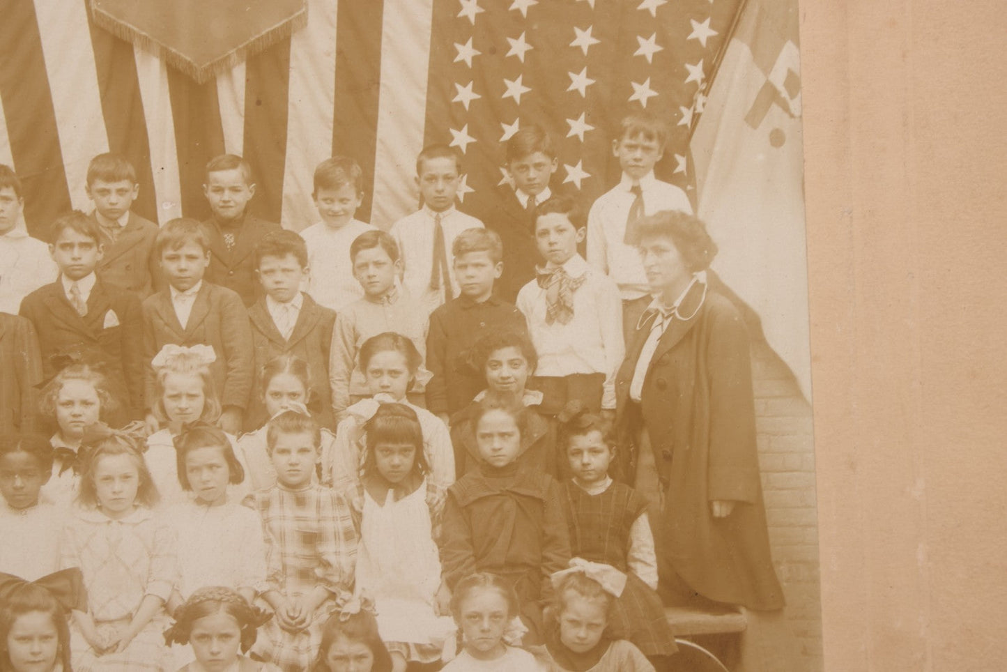 Lot 069 - Antique Boarded Photograph Of An Integrated Elementary School Class, Posing With Large 48 Star American Flag Bunting And Patriotic Decor, Pennants From P.S. 73, Teacher In Photo, Circa 1895