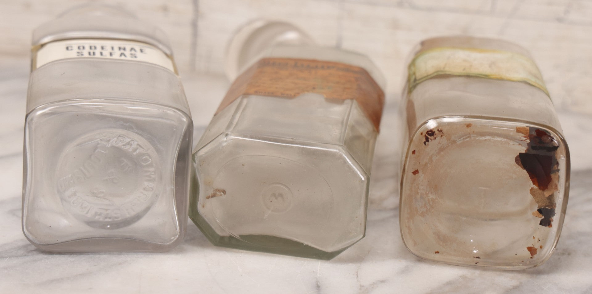 Lot 081 - Grouping Of Three Antique Clear Glass Apothecary Bottles Including Codeinae Sulfas F&S St. Louis, Bottle With Illegible Paper Label, And Otto Jafnel Pharmacist Liberty Ny
