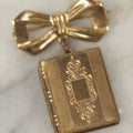Lot 123 - Vintage Gold-Tone Bow Brooch With Dangling Book-Form Locket Monogrammed “M & B”