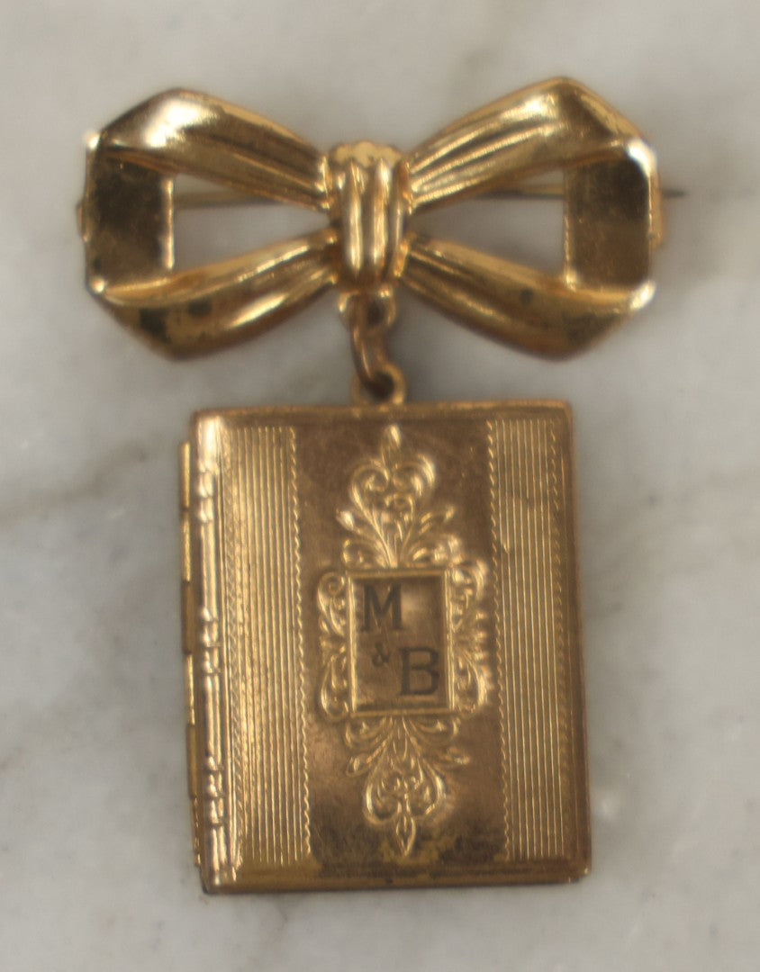 Lot 123 - Vintage Gold-Tone Bow Brooch With Dangling Book-Form Locket Monogrammed “M & B”