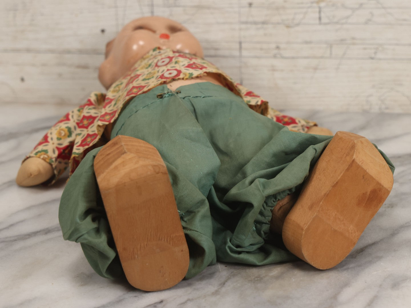 Lot 086 - Vintage Composition Head Googly Eye Baby Doll With Wooden Feet And Cloth Body, Wearing Patterned Shirt And Green Pants, 15-1/2" H