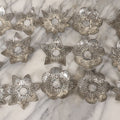 Lot 198 - Grouping Of 16 Pressed Tin Candle Wax Drip Holders In Starburst, Flower, And Star Designs
