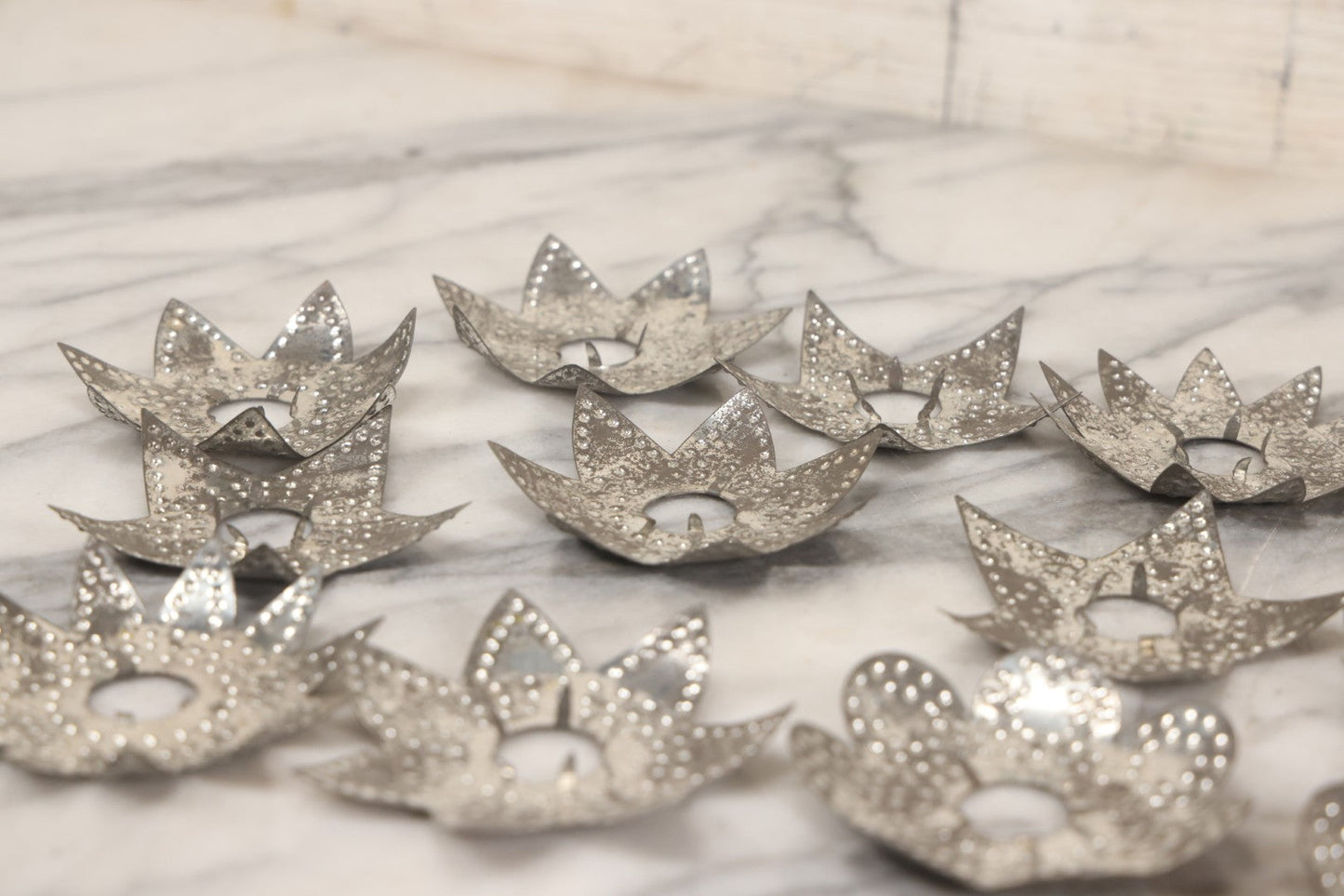 Lot 198 - Grouping Of 16 Pressed Tin Candle Wax Drip Holders In Starburst, Flower, And Star Designs