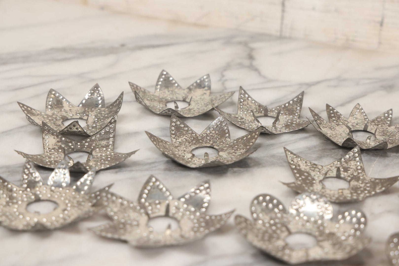 Lot 198 - Grouping Of 16 Pressed Tin Candle Wax Drip Holders In Starburst, Flower, And Star Designs
