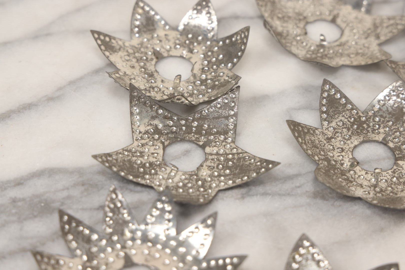 Lot 198 - Grouping Of 16 Pressed Tin Candle Wax Drip Holders In Starburst, Flower, And Star Designs