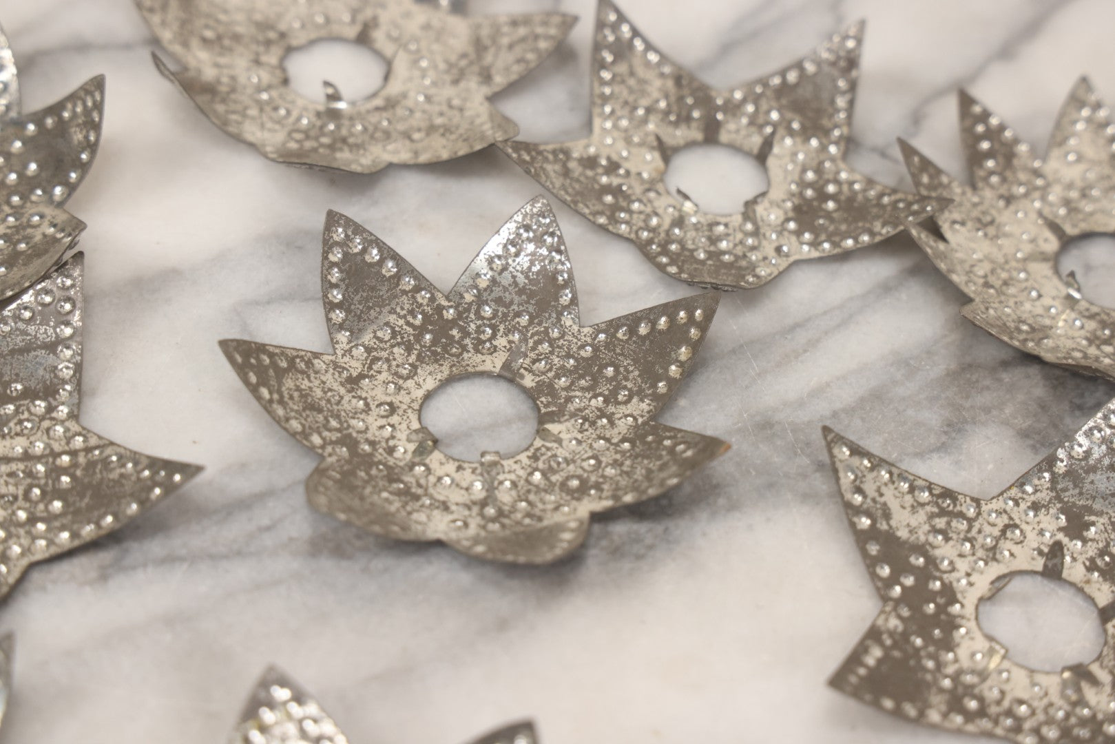 Lot 198 - Grouping Of 16 Pressed Tin Candle Wax Drip Holders In Starburst, Flower, And Star Designs