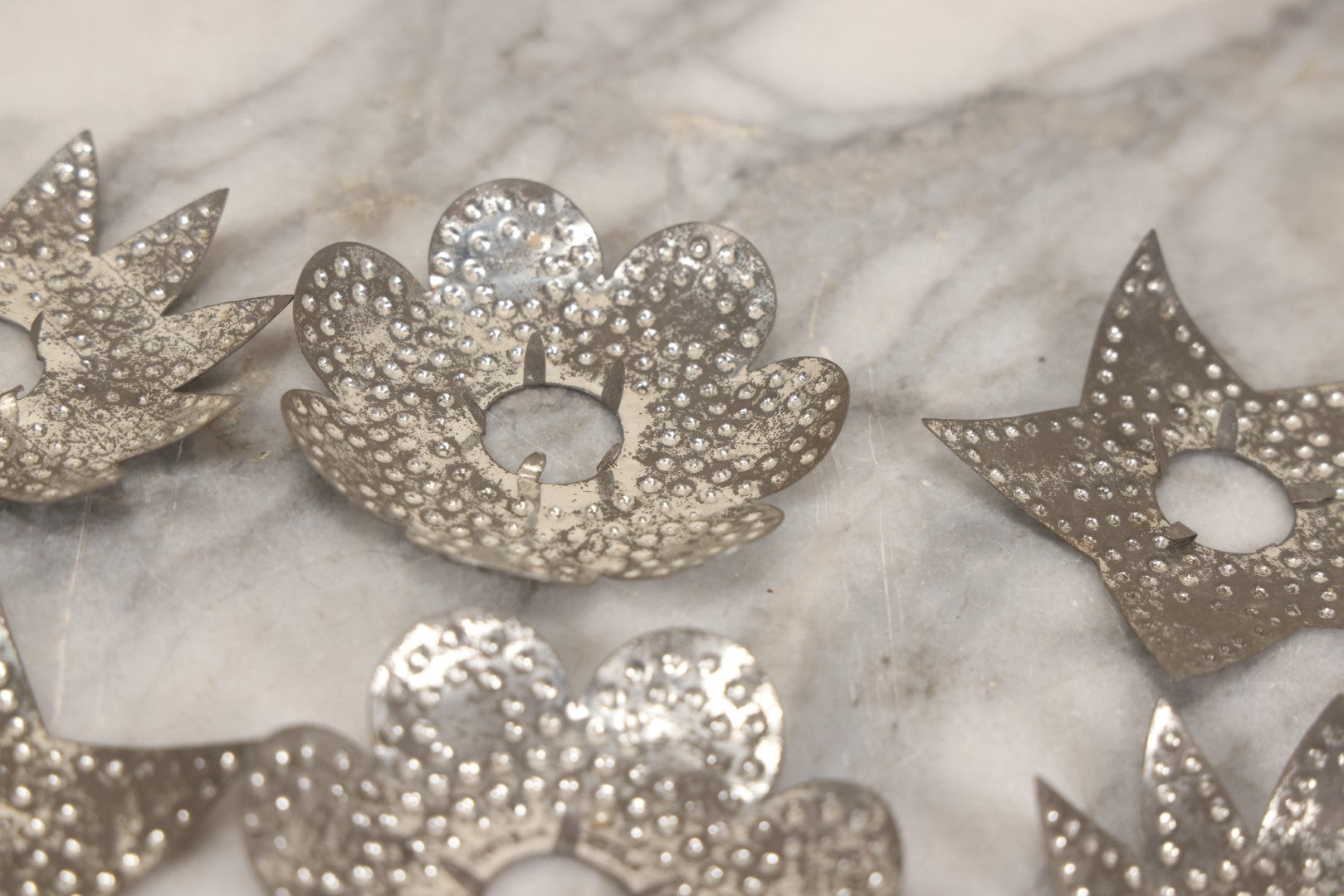 Lot 198 - Grouping Of 16 Pressed Tin Candle Wax Drip Holders In Starburst, Flower, And Star Designs