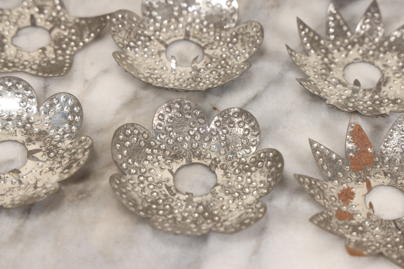 Lot 198 - Grouping Of 16 Pressed Tin Candle Wax Drip Holders In Starburst, Flower, And Star Designs