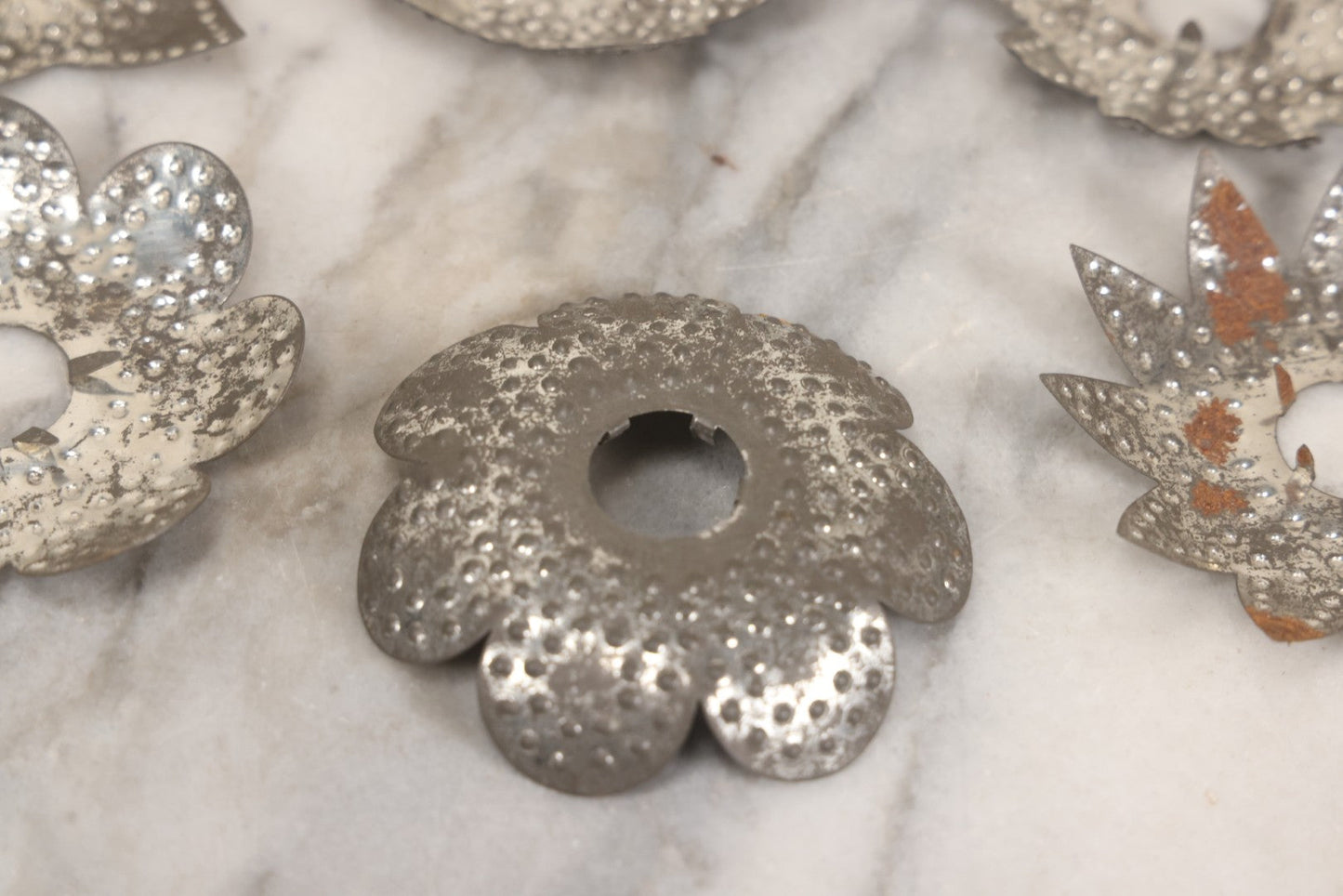Lot 198 - Grouping Of 16 Pressed Tin Candle Wax Drip Holders In Starburst, Flower, And Star Designs