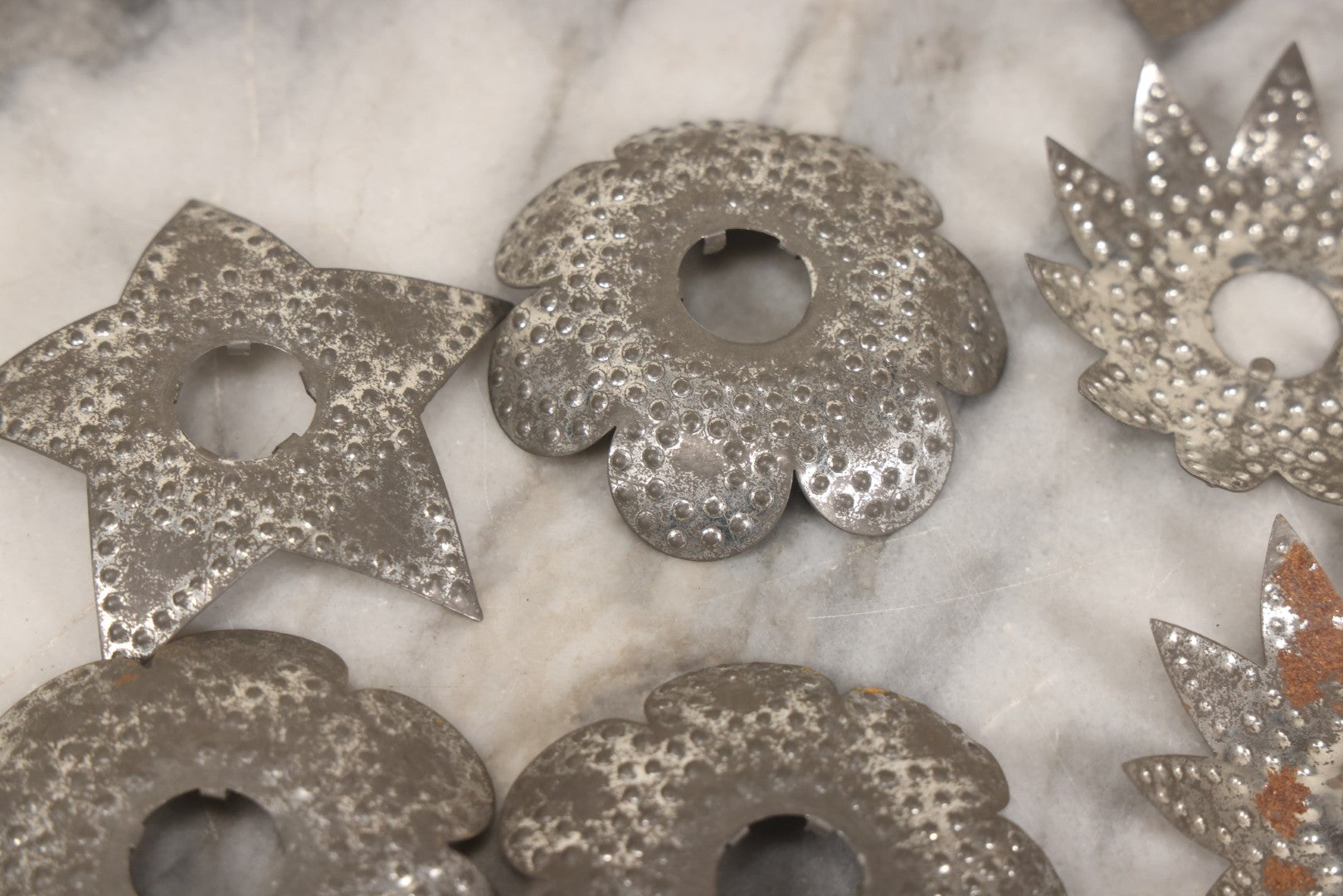 Lot 198 - Grouping Of 16 Pressed Tin Candle Wax Drip Holders In Starburst, Flower, And Star Designs