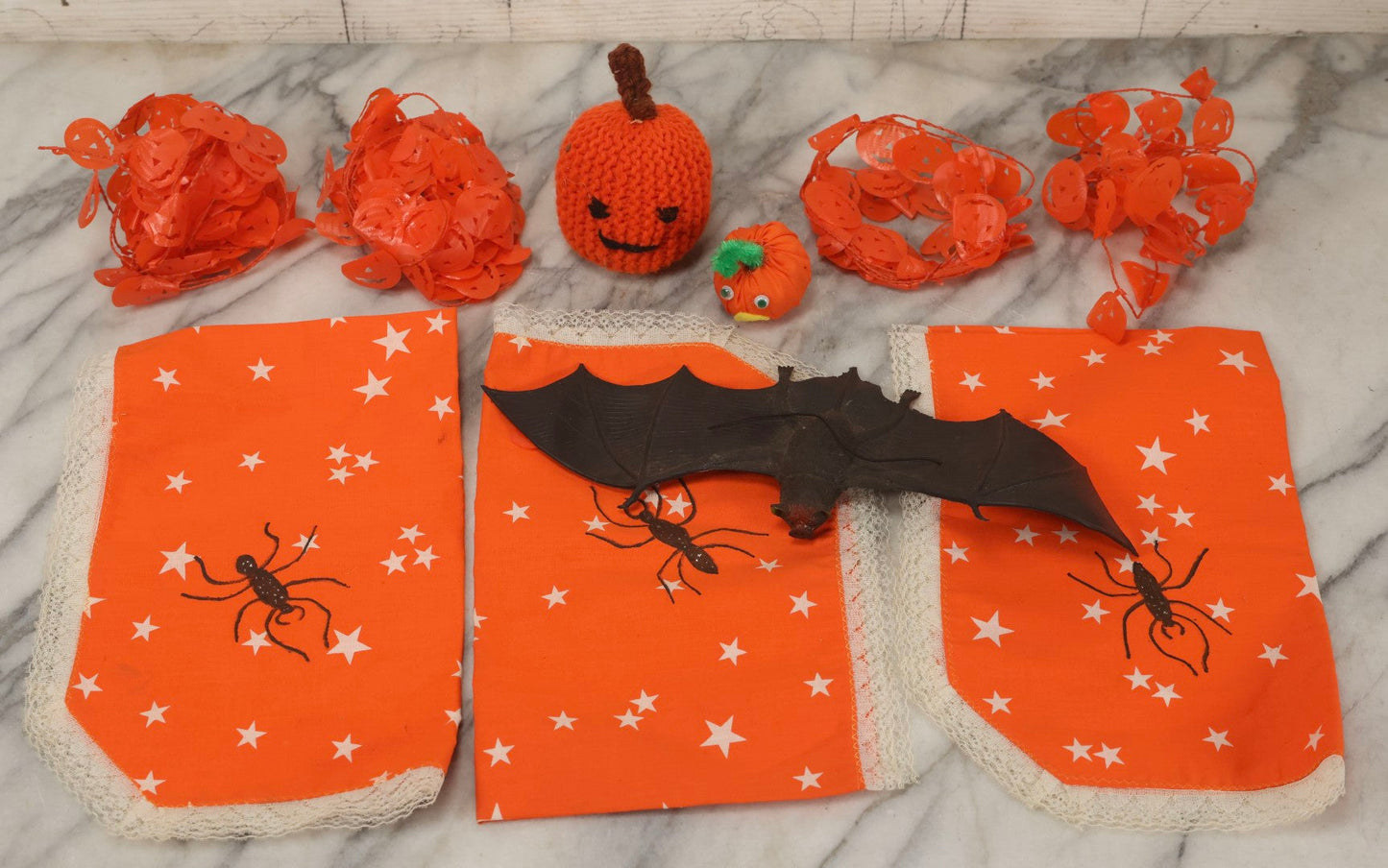Lot 090 - Grouping Of Hallowe'en Toys And Crafts, Including Rubber Bat, Stuffed Knit Pumpkin, Three Painted Spider Placemats, Four Jack-O-Lantern Cellophane Garlands, And Google-Eyed Jack-O-Lantern Pin Cushion