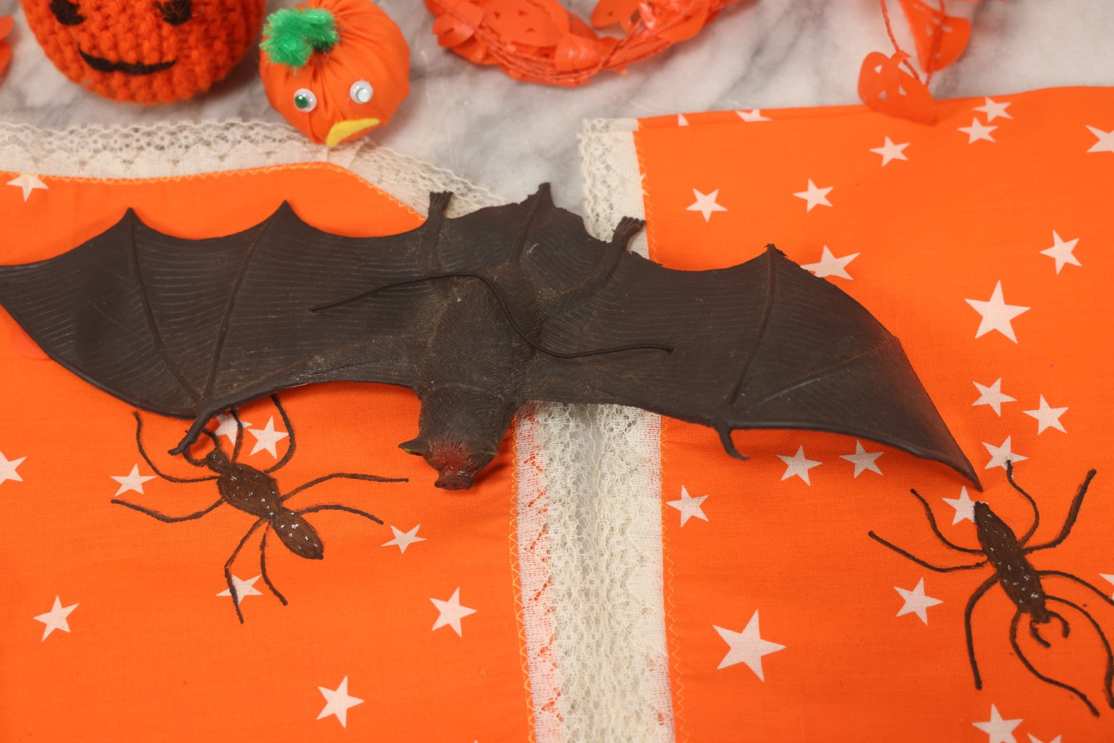 Lot 090 - Grouping Of Hallowe'en Toys And Crafts, Including Rubber Bat, Stuffed Knit Pumpkin, Three Painted Spider Placemats, Four Jack-O-Lantern Cellophane Garlands, And Google-Eyed Jack-O-Lantern Pin Cushion