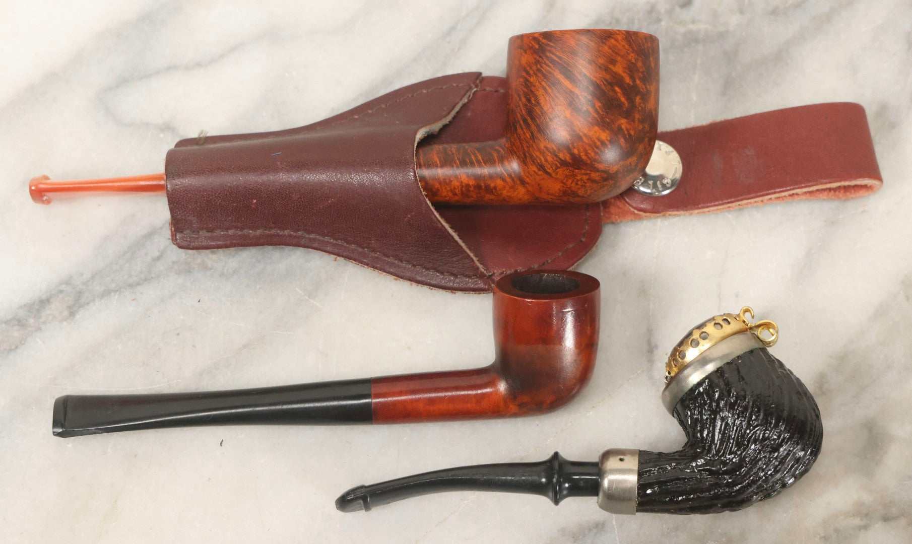 Lot 099 - Grouping Of Three Vintage Pipes Including Genuine Briar, Wood Grain With Sheath, And Painted Wood With Brass Cover