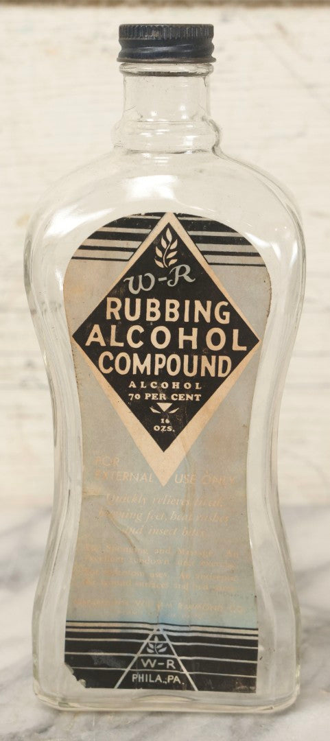 Lot 112 - Vintage W-R Rubbing Alcohol Compound Clear Glass Bottle With Paper Label And Original Cap, 70 Percent Alcohol, Manufactured By William Raymond Co., Philadelphia, Pennsylvania, 8-1/4" H