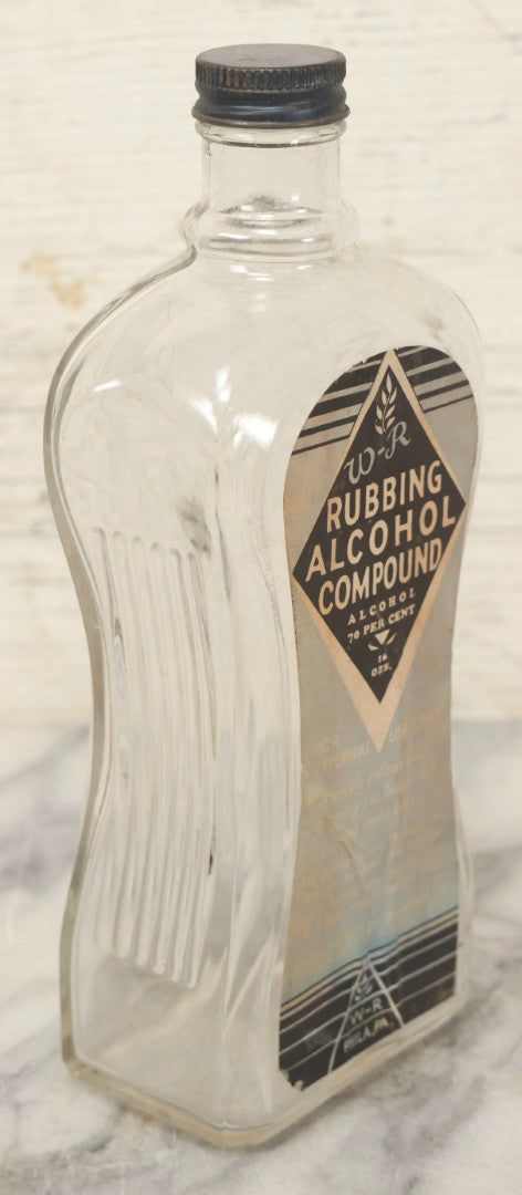 Lot 112 - Vintage W-R Rubbing Alcohol Compound Clear Glass Bottle With Paper Label And Original Cap, 70 Percent Alcohol, Manufactured By William Raymond Co., Philadelphia, Pennsylvania, 8-1/4" H