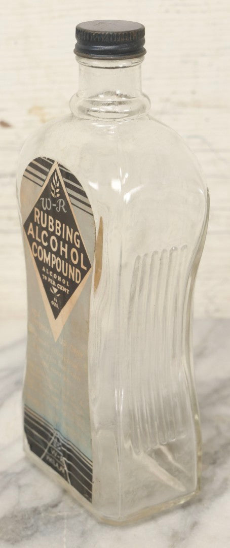 Lot 112 - Vintage W-R Rubbing Alcohol Compound Clear Glass Bottle With Paper Label And Original Cap, 70 Percent Alcohol, Manufactured By William Raymond Co., Philadelphia, Pennsylvania, 8-1/4" H