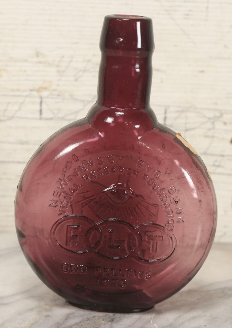 Lot 114 - Vintage Odd Fellows And Rebekah Commemorative Purple Glass Bottle, “New Jersey Eye Bank Visual Research Foundation,” 1973, With All-Seeing-Eye And F.L.T. Three Links, Clevenger Bros. Glass Works, Clayton, New Jersey, 7" H