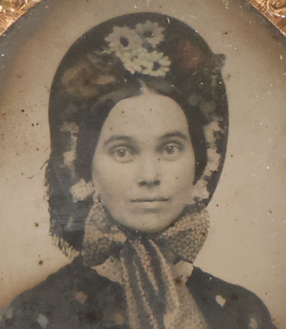 Lot 164 - Antique Oval-Cut Tintype Photograph Of Woman In Bonnet With Flowers And Bow Scarf, In Brown Thermoplastic “Oreo”-Style Case With Brass Preserver, 1-7/8" x 2-1/8"