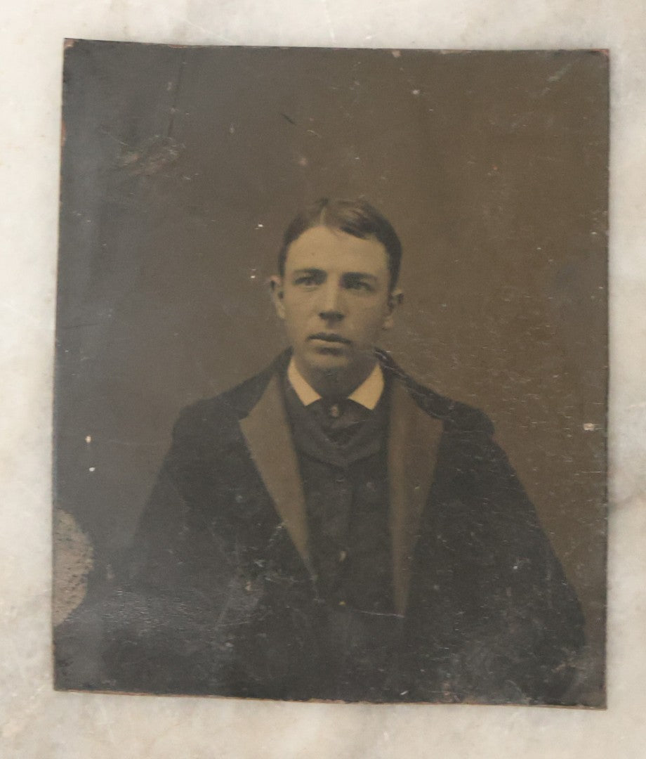 Lot 165 - Grouping Of Three Antique Portrait Photographs, One Tintype Of A Young Man, Two Ruby Ambrotypes In Brass Mats Including Young Woman With Hand-Painted Jewelry And Young Man In Bowtie