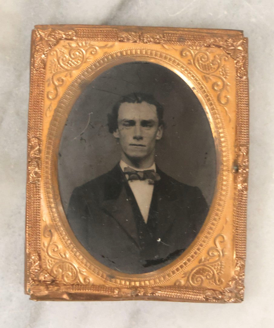 Lot 165 - Grouping Of Three Antique Portrait Photographs, One Tintype Of A Young Man, Two Ruby Ambrotypes In Brass Mats Including Young Woman With Hand-Painted Jewelry And Young Man In Bowtie