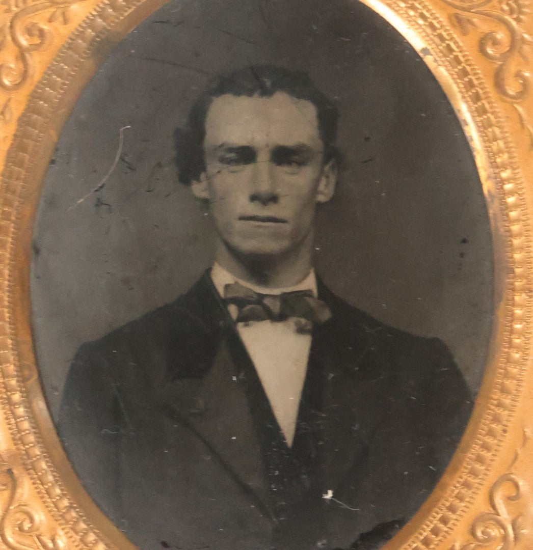 Lot 165 - Grouping Of Three Antique Portrait Photographs, One Tintype Of A Young Man, Two Ruby Ambrotypes In Brass Mats Including Young Woman With Hand-Painted Jewelry And Young Man In Bowtie